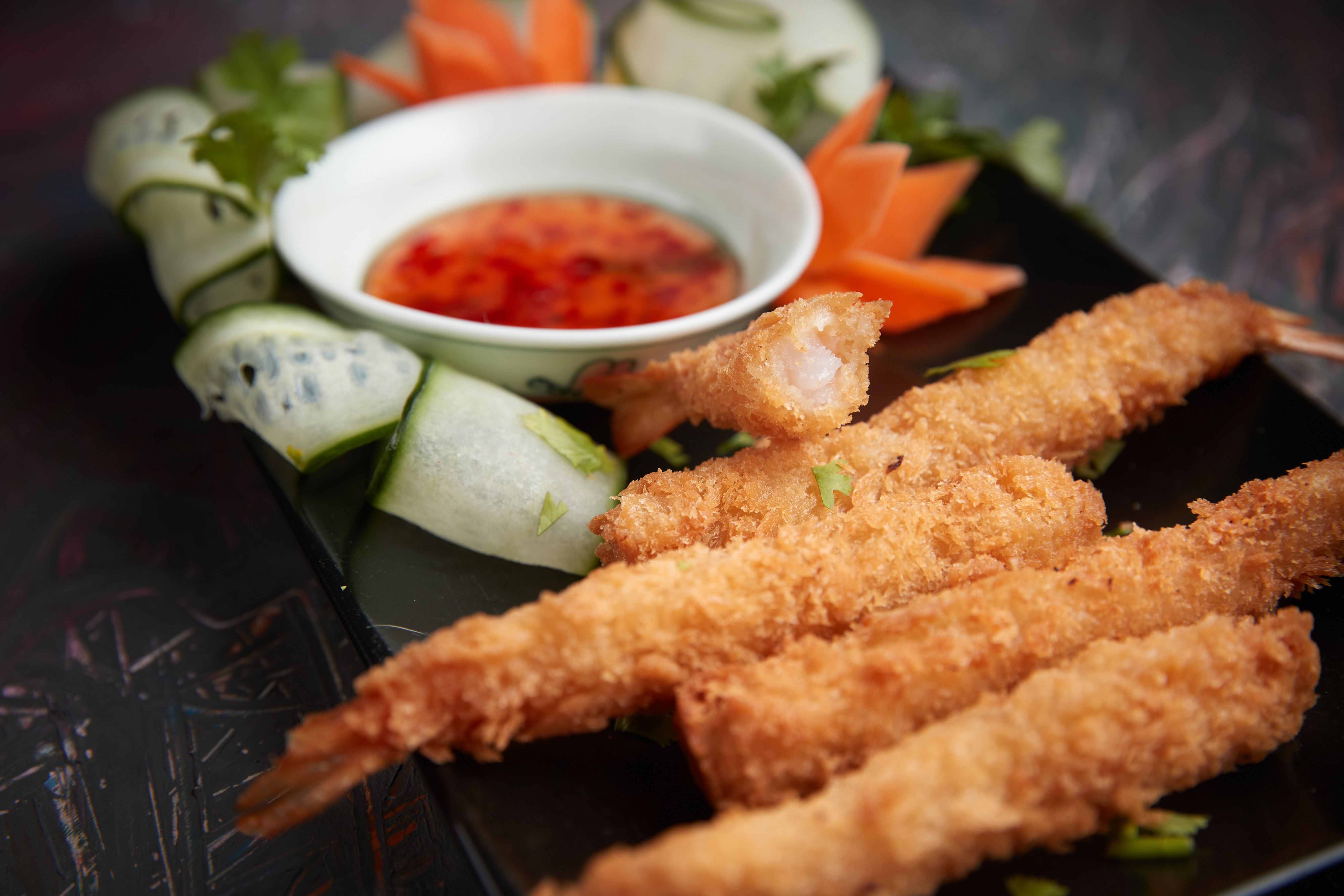 Delicious deep-fried panko shrimp served with a sweet chili dipping sauce and garnished with fresh vegetables.