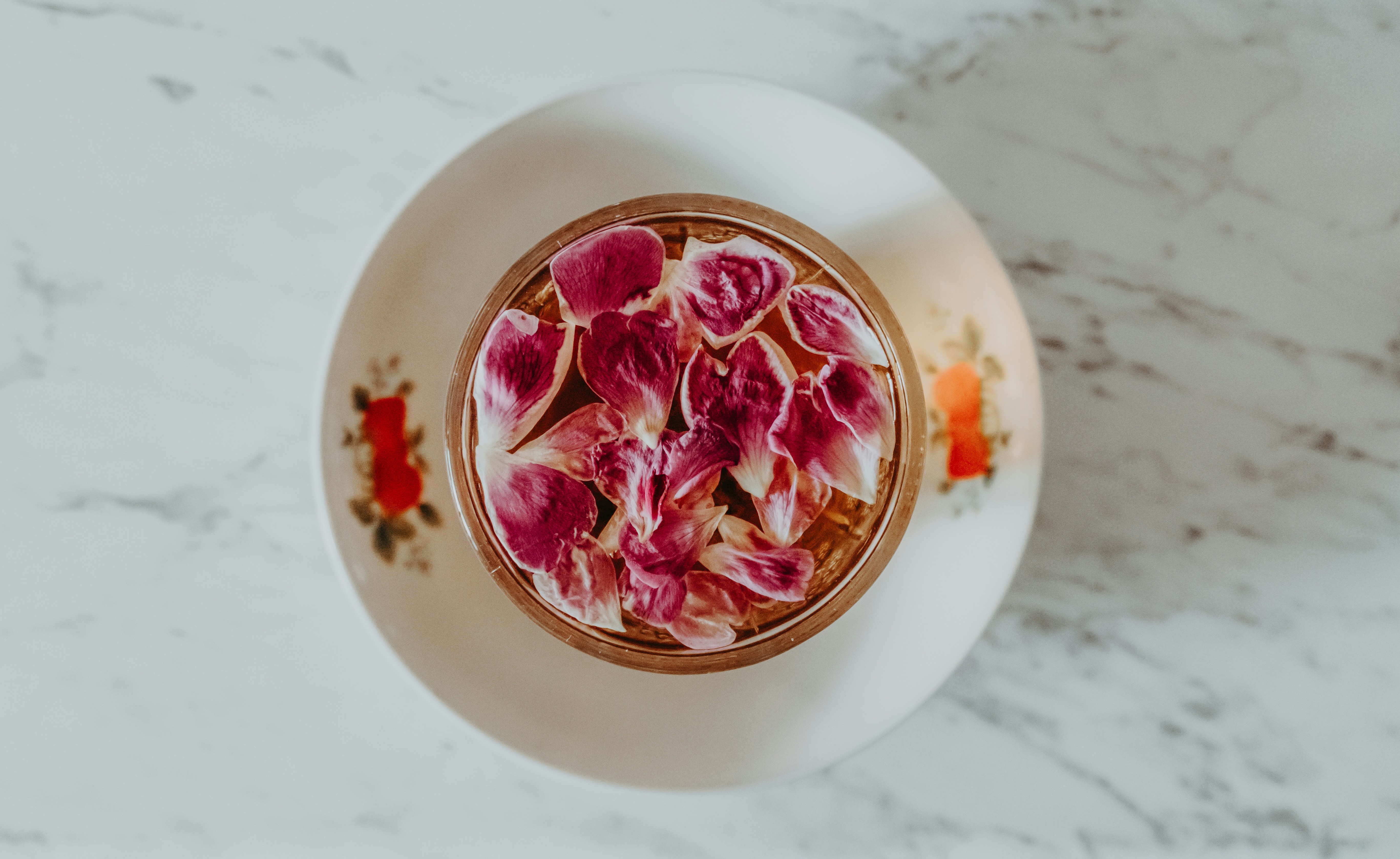 A small bowl of pink flower petals on a plate.