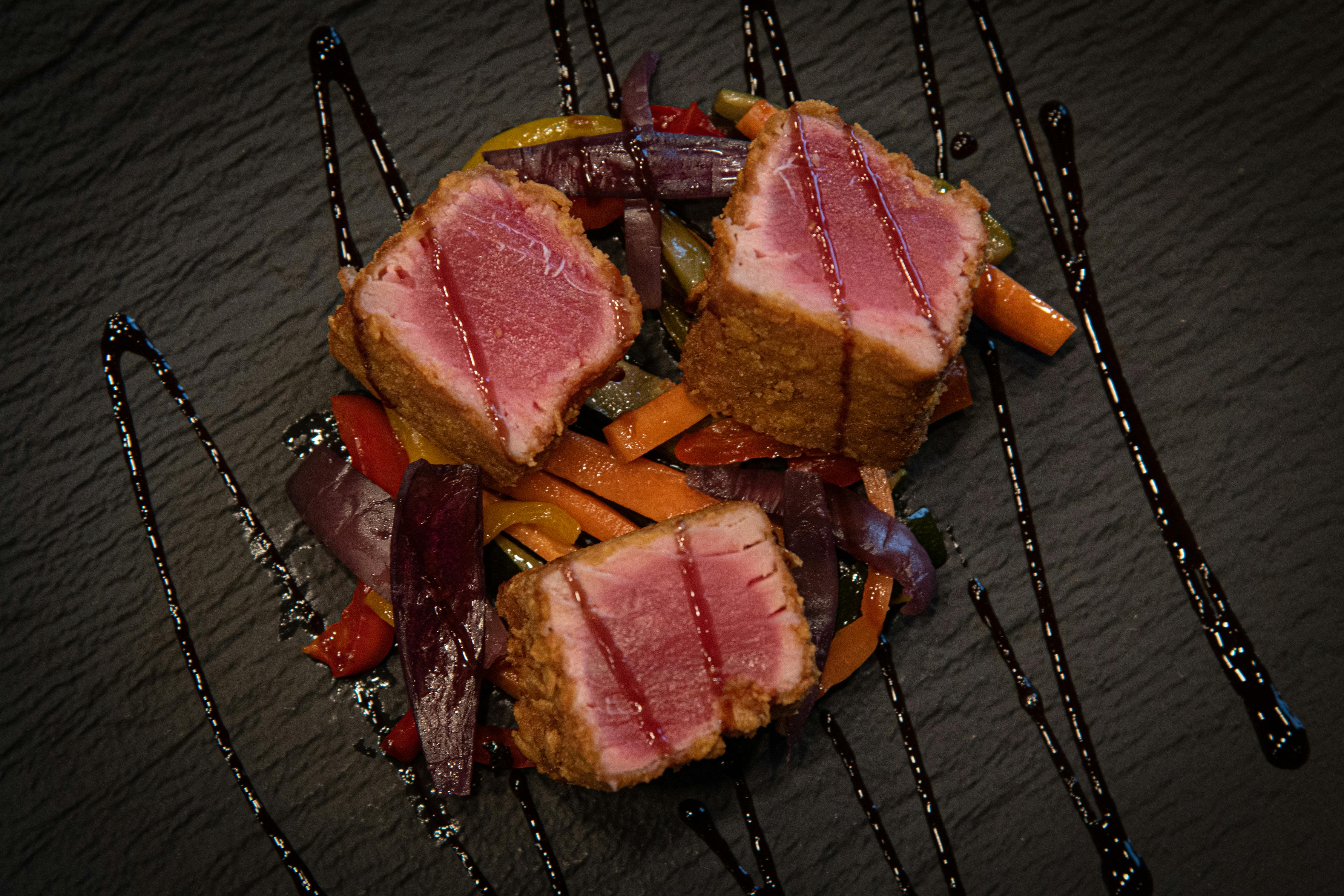 A delicious plate of seared tuna with vibrant vegetables, artfully presented.