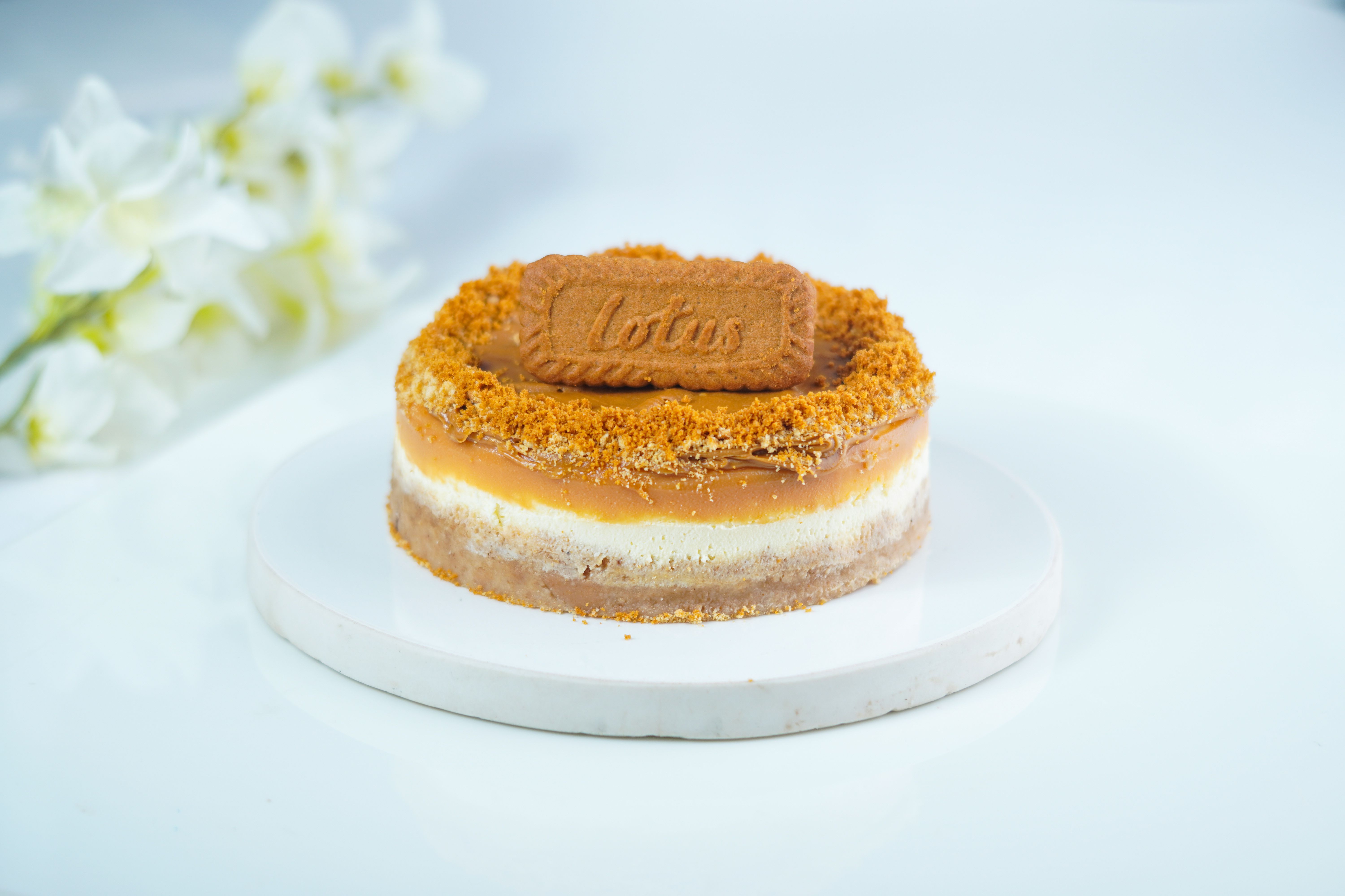Indulge in a caramel Biscoff cheesecake on a white plate with flowers.